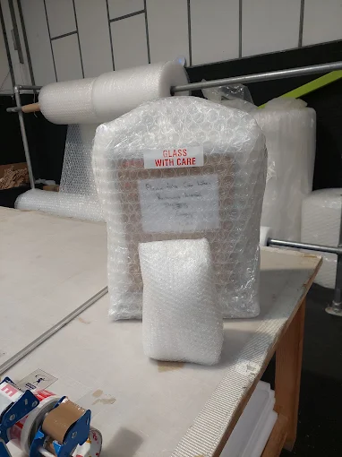 Bubble-wrapped fragile items with foam protection on the Quays packing bench